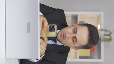 Vertical-video-of-Home-office-worker-man-gets-frustrated-while-looking-at-phone.